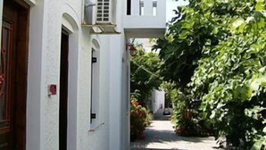 Un estrecho callejón con edificios blancos, una puerta de madera y un farol colgante.