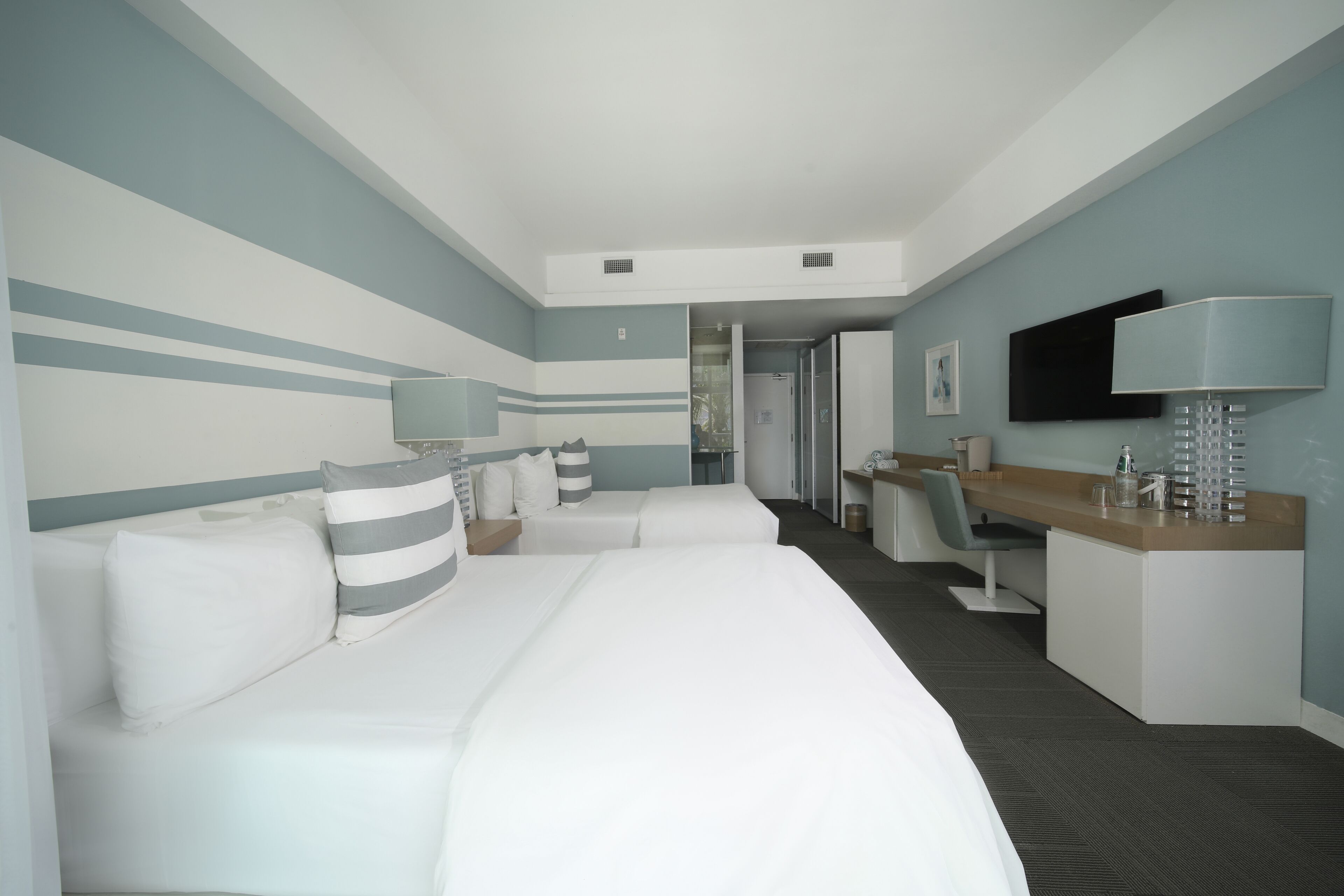 Una camera d'albergo moderna con un letto grande, una scrivania e una televisione.