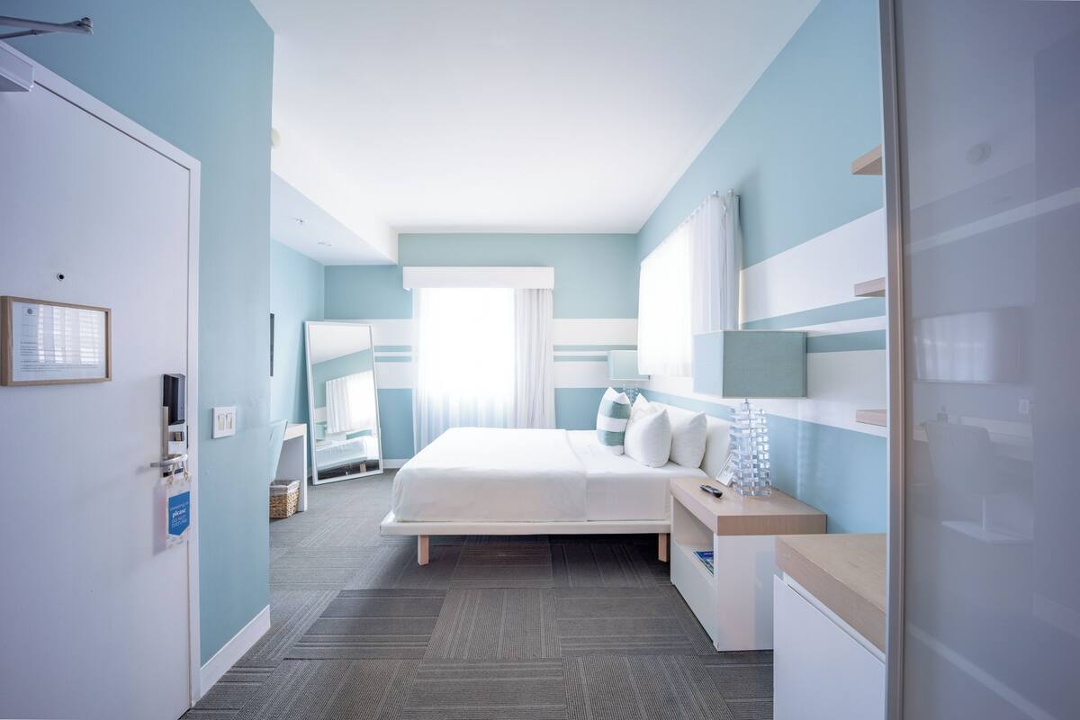 Une chambre d’hôtel avec un lit, une table de chevet et une fenêtre avec des rideaux.