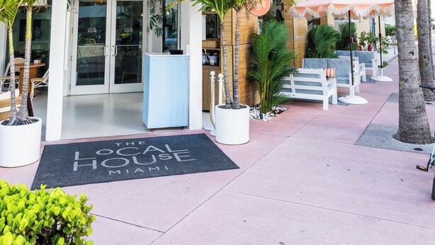 A hotel with a modern design, featuring a prominent entrance, outdoor seating area, and a balcony. - The Local House (Miami Beach)