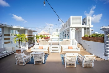 A hotel interior with a ceiling decorated with tropical leaf patterns, a modern staircase, and a view of palm trees outside. at The Local House