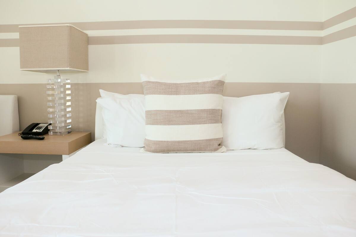 Une chambre d’hôtel avec un lit, une table de chevet avec une lampe et un téléphone.