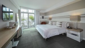 A hotel room with a bed, bedside table, desk, and a balcony with chairs. - The Local House (Miami Beach)