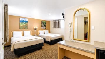 Habitación de hotel con dos camas, un espejo grande, un escritorio y un baño pequeño.