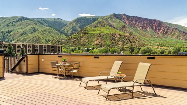 Une terrasse avec des sièges extérieurs et une vue sur des collines verdoyantes et une montagne.