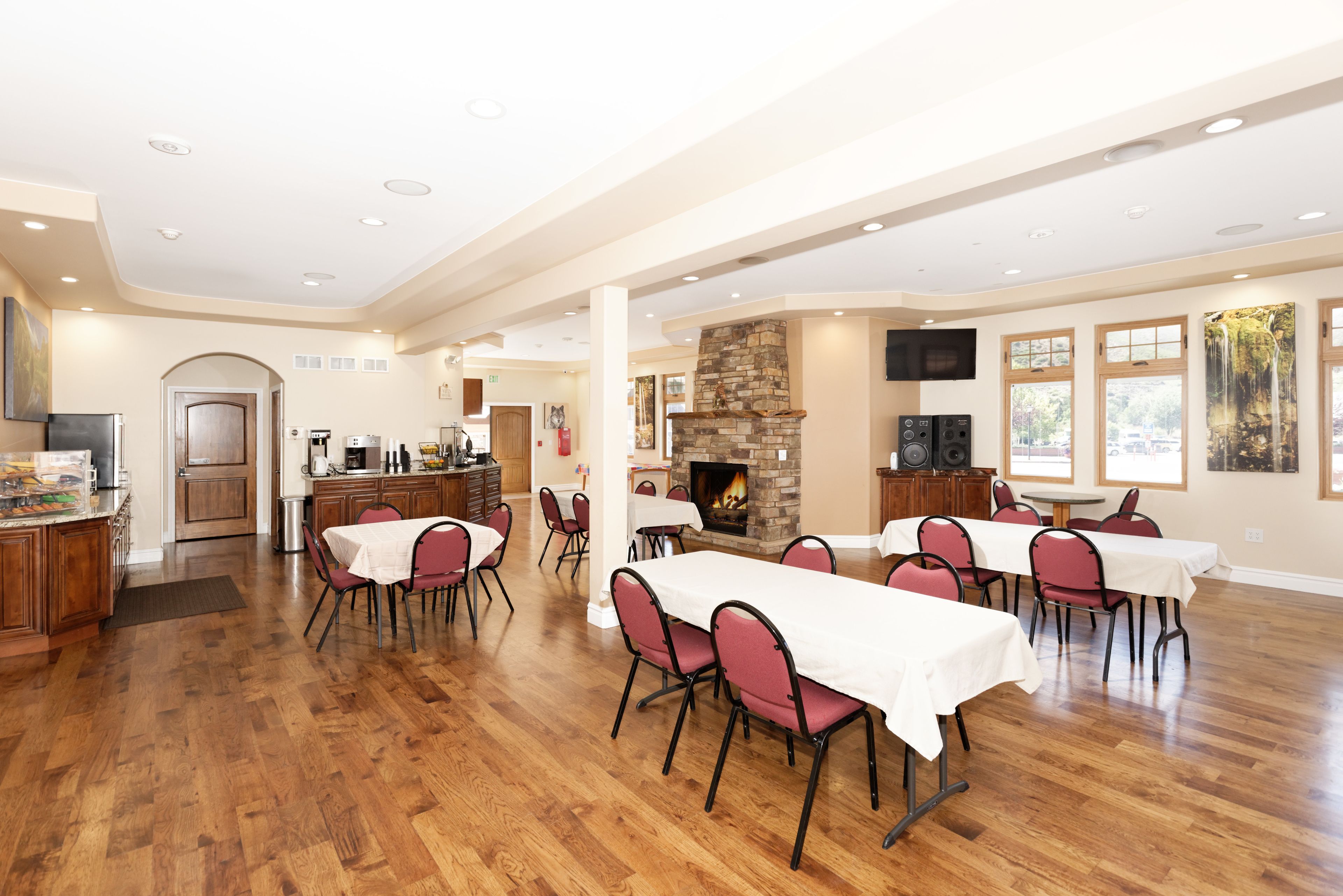A spacious dining area with a stone fireplace, wooden flooring, and large windows.