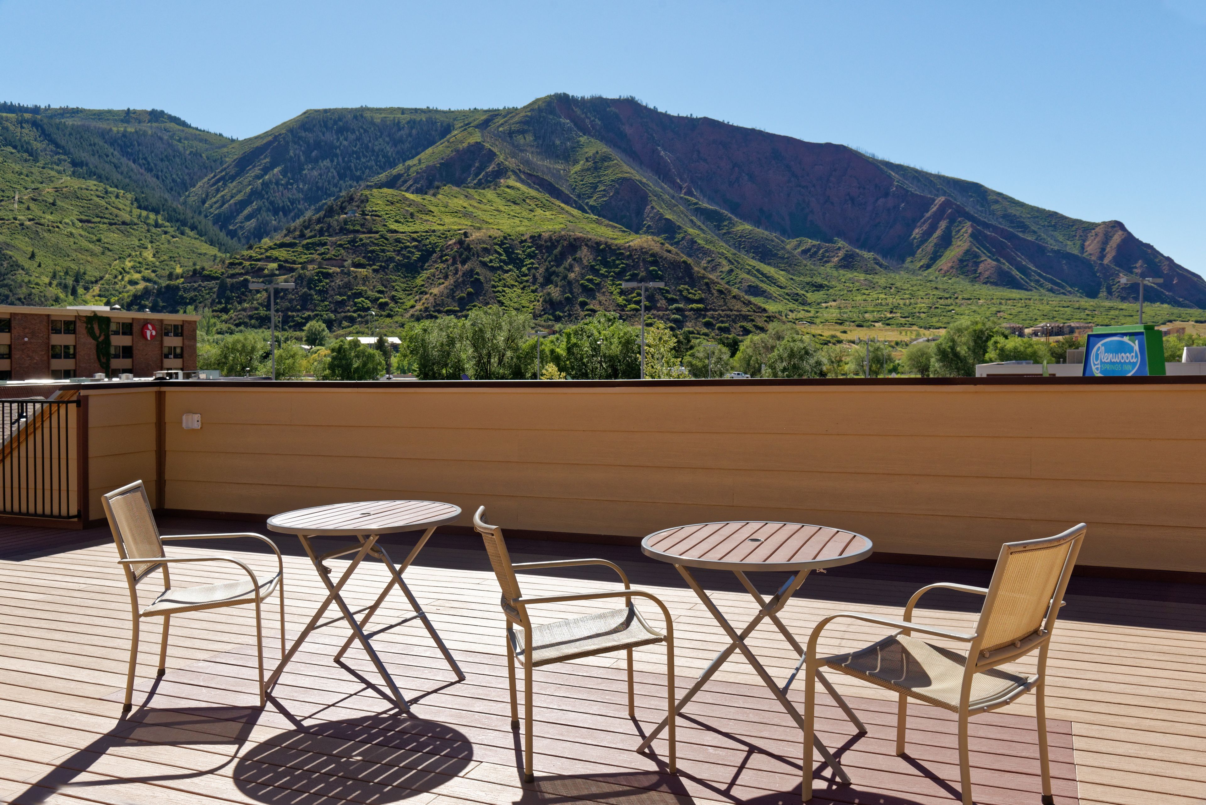 Une terrasse dotée de tables et de chaises, offrant une vue sur un paysage montagneux.