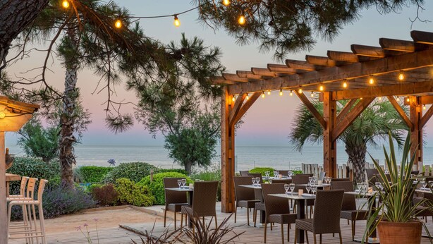 An outdoor dining area with wooden pergolas, string lights, and tables set for dining. - Paradou Mediterranee, BW Signature Collection (Sausset-les-Pins)