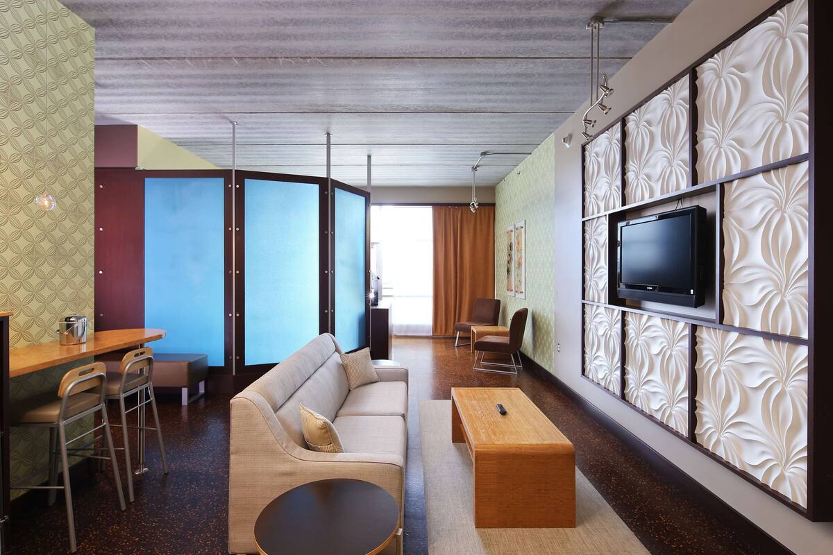 Een moderne woonkamer met een bank, salontafel en een televisie bevestigd aan een decoratieve wand.