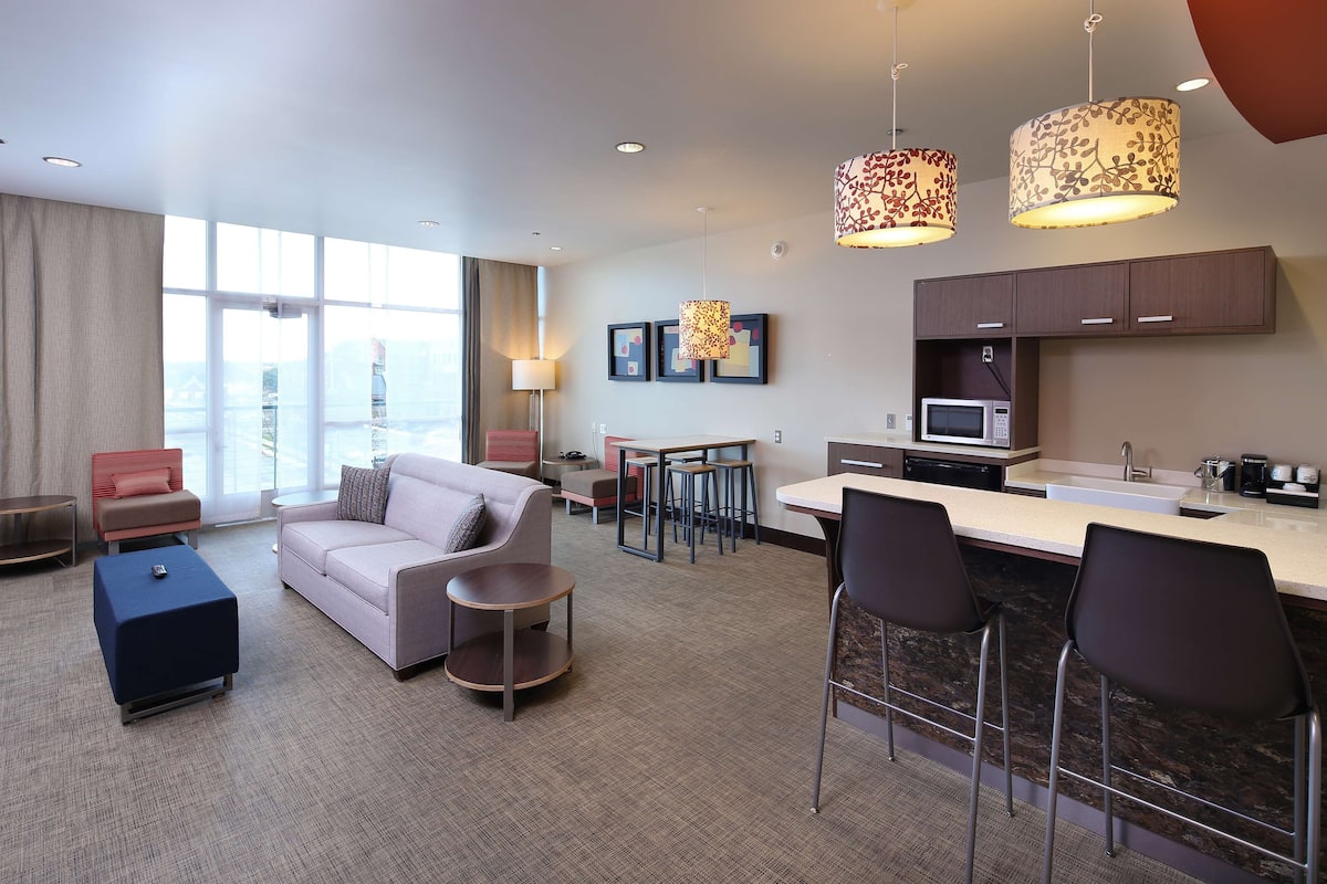 Een moderne hotelkamer met een zithoek, een kitchenette en een eethoek.