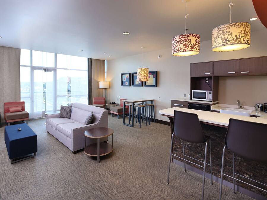Une chambre d’hôtel moderne dotée d’un coin salon, d’une kitchenette et d’un espace repas.