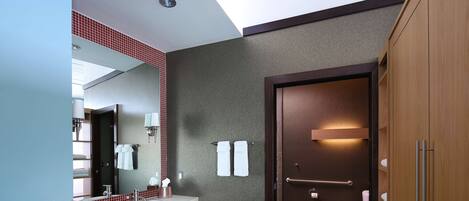 Un baño moderno con lavamanos, espejo y retrete.