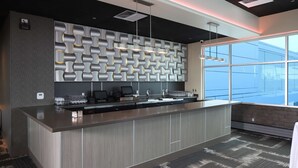 Een moderne receptie met een behangwand, een lange balie met een laptop en een groot raam met uitzicht op het gebouw.