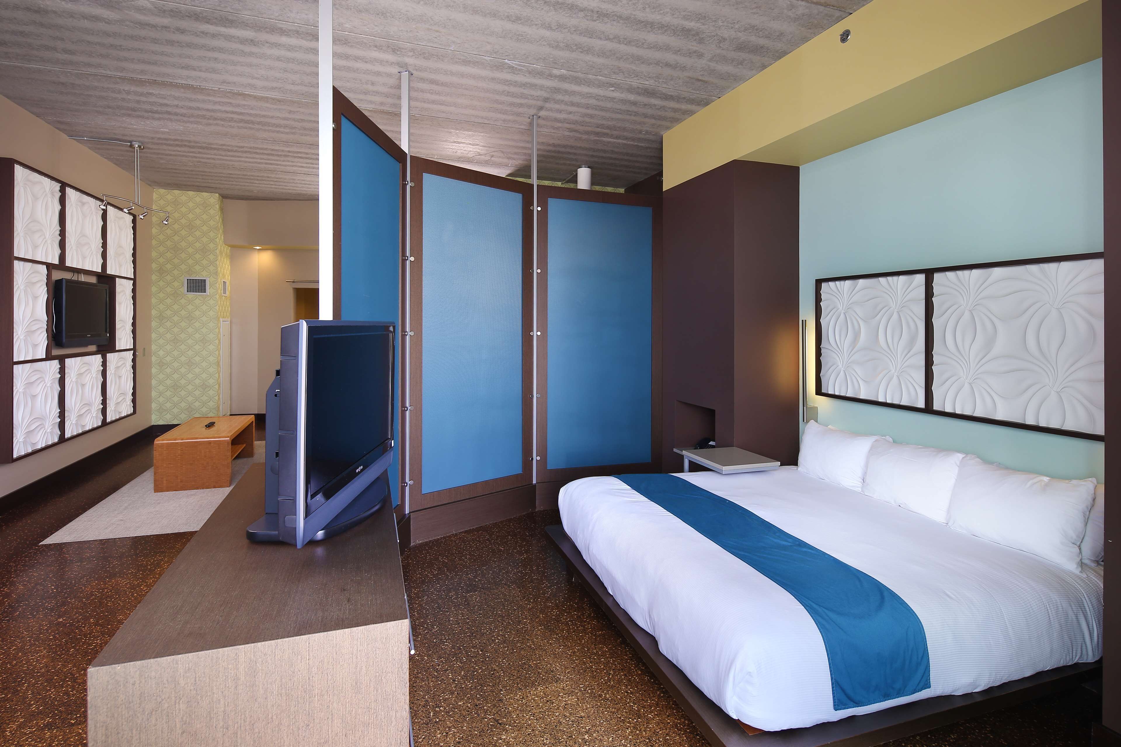 A hotel room with a bed, a TV, a desk, and a wardrobe.