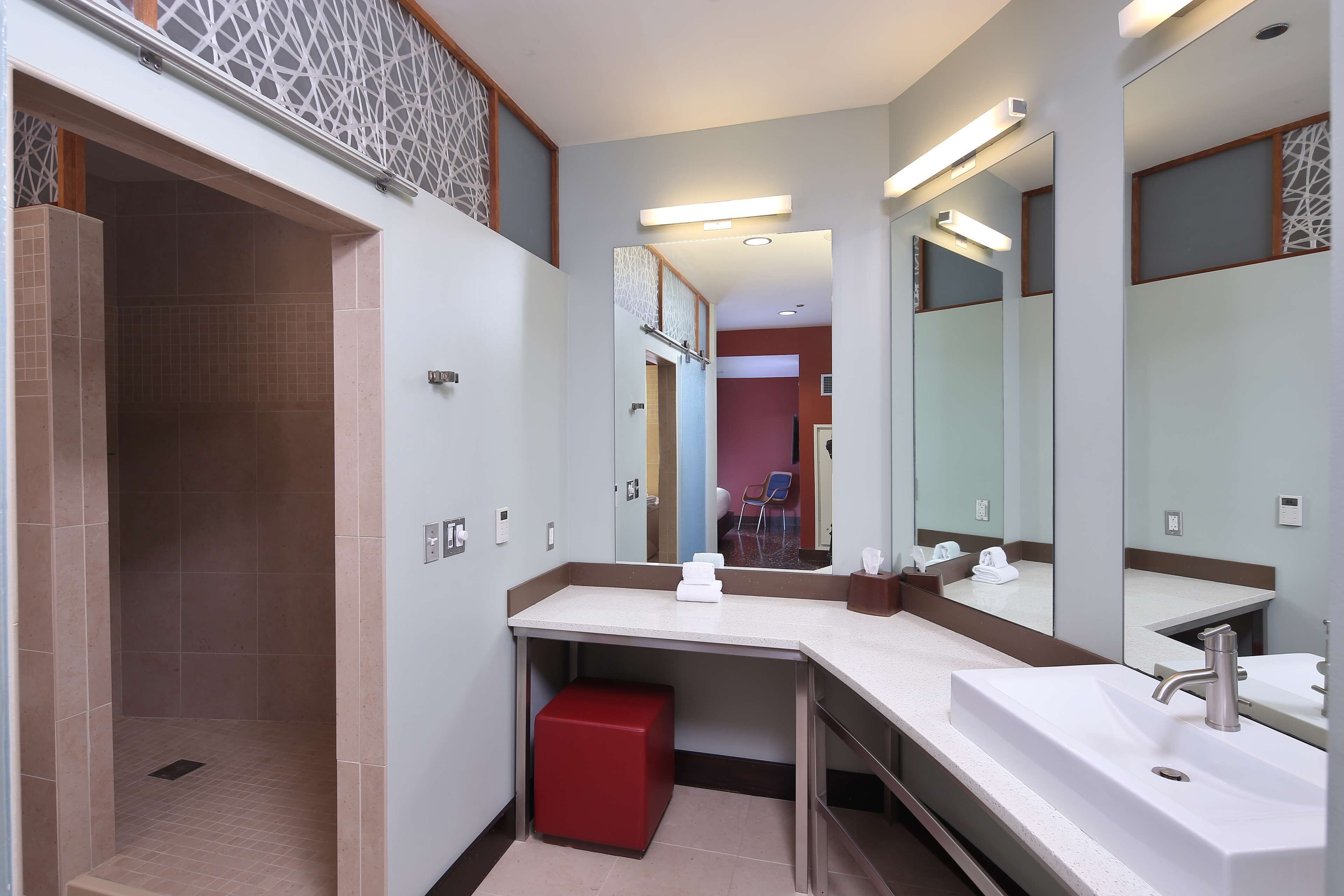 Uma casa de banho moderna com um espelho grande, uma pia e uma zona de duche.