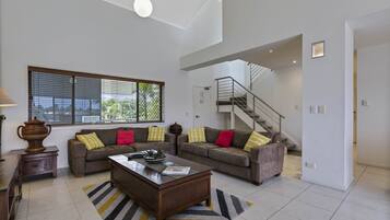 A spacious living room with a large window, a staircase, and a modern kitchen area.