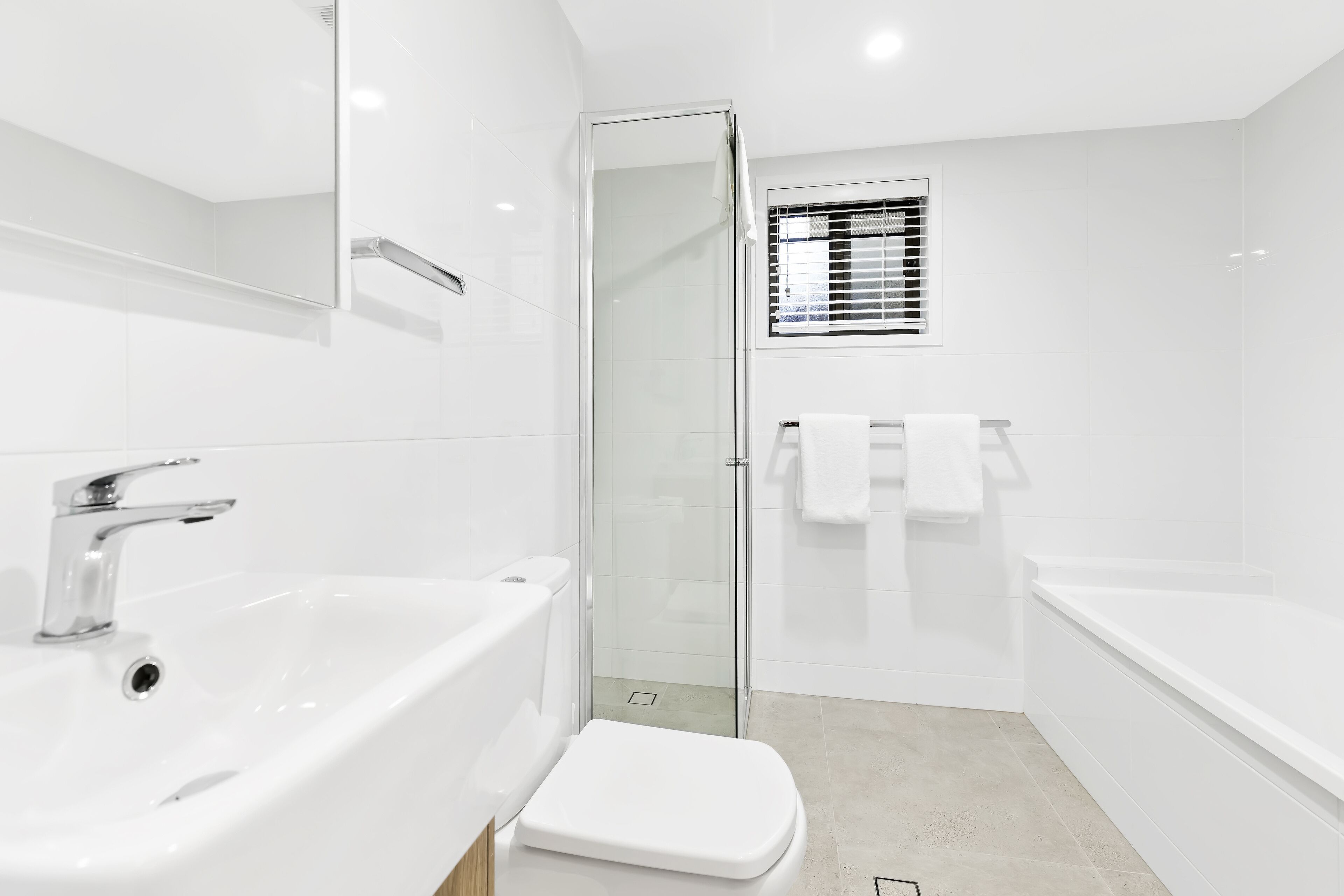 A modern bathroom with a white sink, toilet, and bathtub.