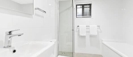 A modern bathroom with a white sink, toilet, and bathtub.