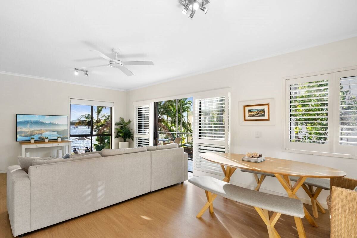 A spacious living area with a sofa, a dining table, and a ceiling fan.