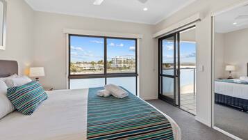 A hotel room with a large bed, a view of the sea, and a sliding door to an outdoor balcony.