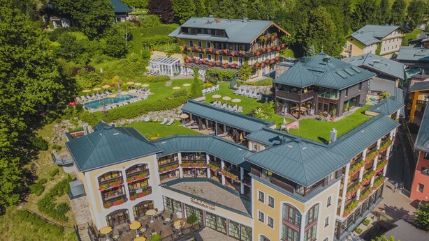 A multi-story hotel with outdoor seating areas and a pool.