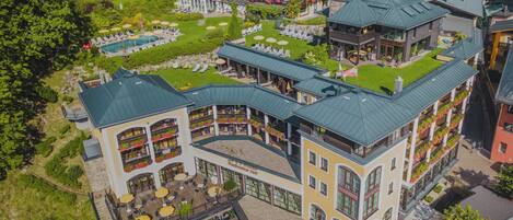 Experience a unique hotel stay with balconies featuring flower boxes, a pool, and sun loungers in a well-maintained outdoor area.