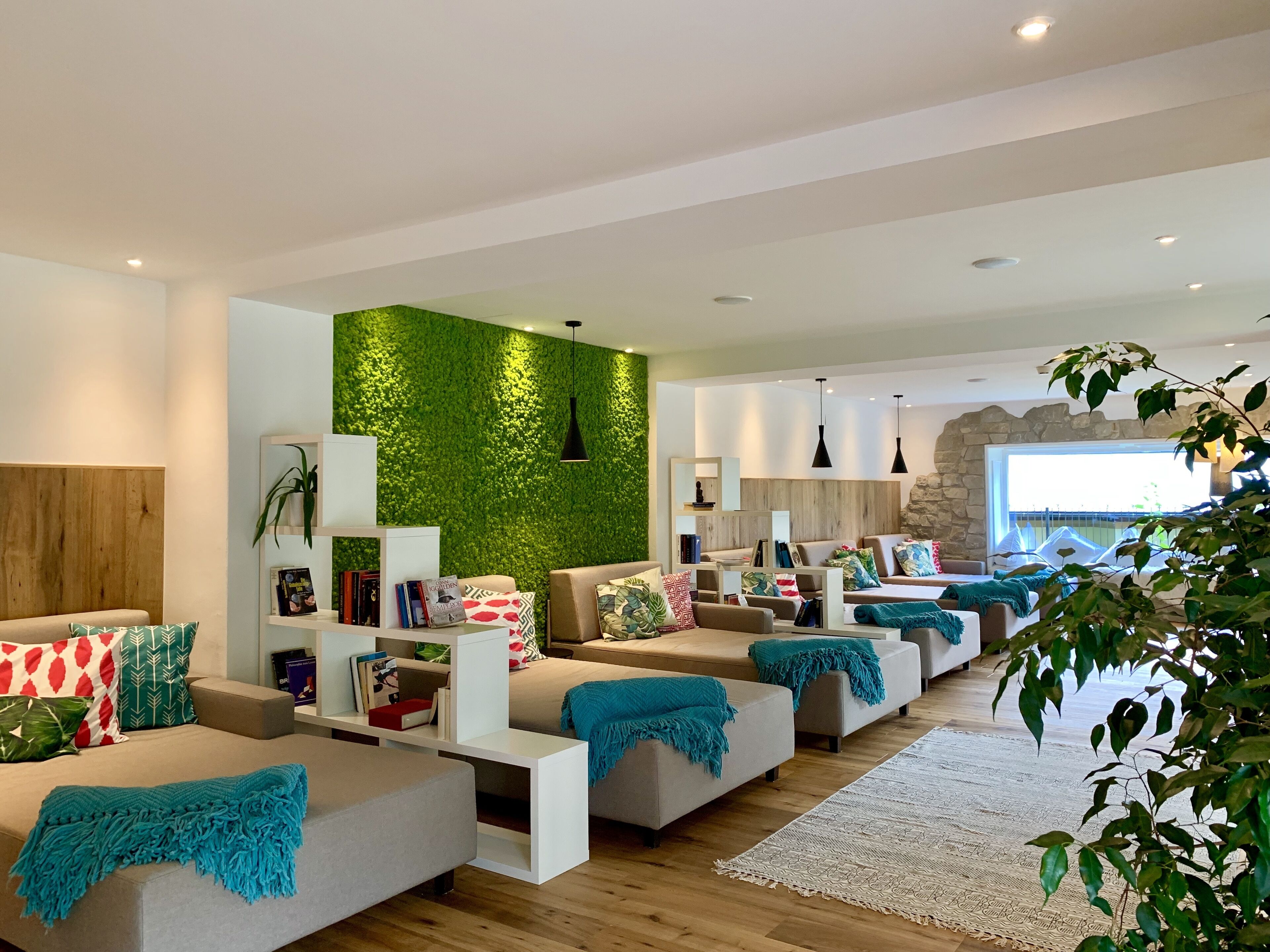 A modern living room with a green wall, multiple seating areas, and a stone accent wall.