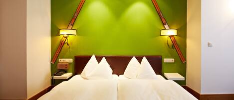 A hotel room with a large bed, green accent wall, and two bedside lamps.