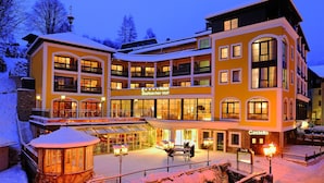 Ein mehrstöckiges Hotel mit verschneiter Fassade, Balkonen und einem gut beleuchteten Eingang.