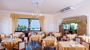 Ein Restaurant mit mehreren Tischen, Meerblick und einer verzierten Decke.