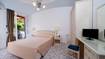 A bedroom with a bed, bedside tables, a desk with a chair, a television, and a wardrobe.