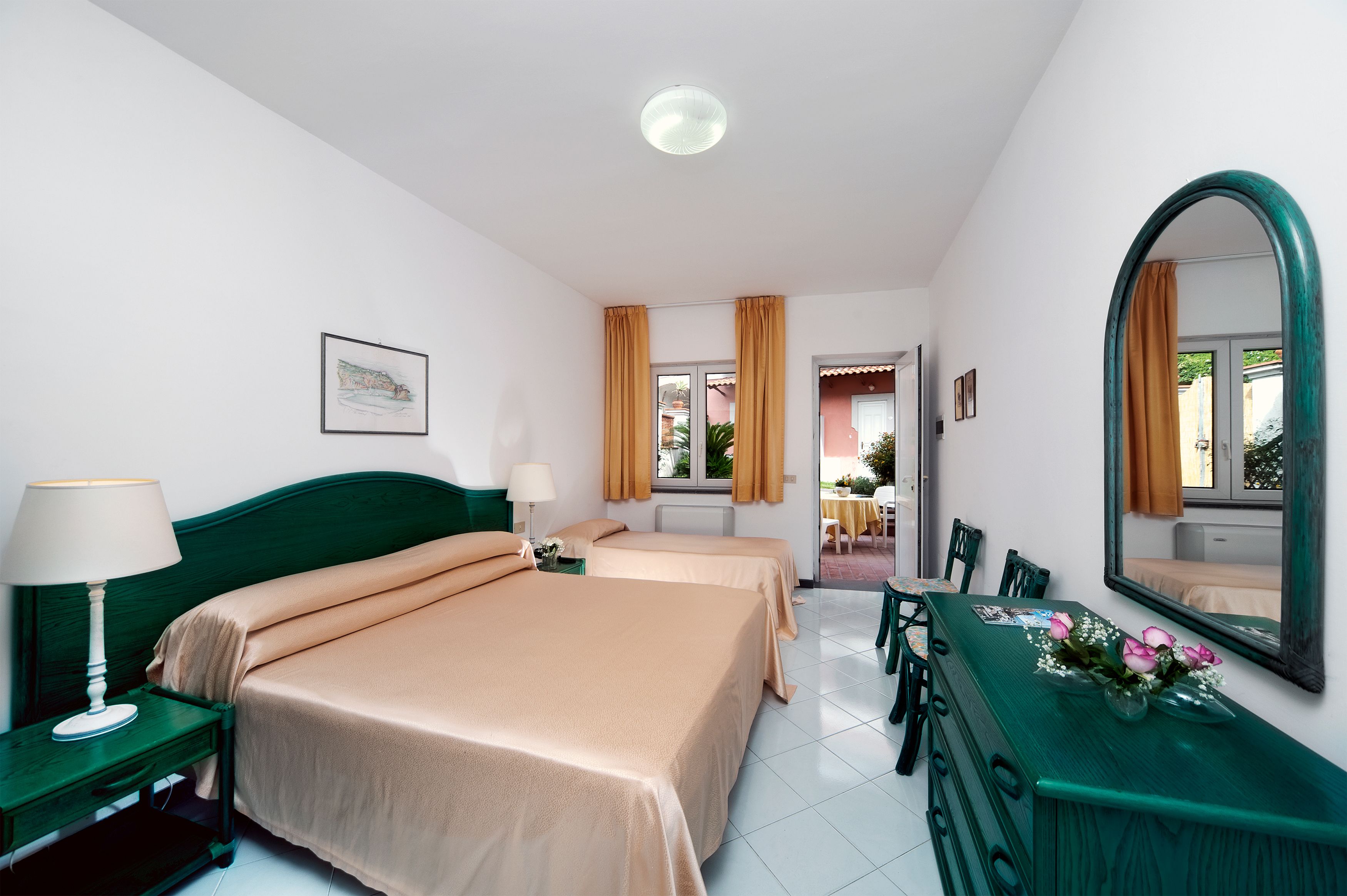 Habitació d'hotel amb dos llits, taula de menjador, cadires, mirall i finestra amb cortines.