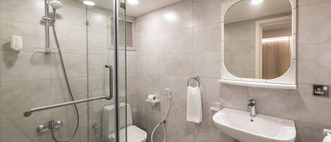 Un baño moderno con ducha envuelta en vidrio, inodoro, lavabo y espejo.