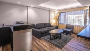 A modern hotel room with a sofa, a small table, a chair, and a dining table. - Oasis Hotel Kuwait (Kuwait City)