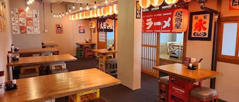 A restaurant interior with wooden tables and stools, string lights, and Japanese decor.