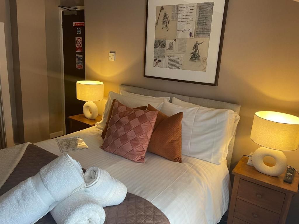 Une chambre d’hôtel avec un lit, deux lampes de chevet, une œuvre d’art encadrée au mur et une porte avec une pancarte.