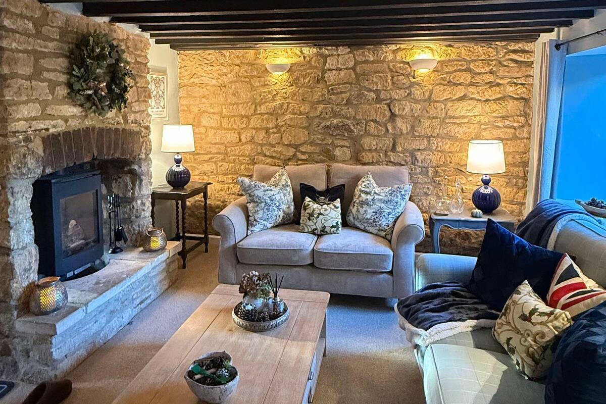 A cozy living room with a stone fireplace, a sofa set, a coffee table, and a lamp.