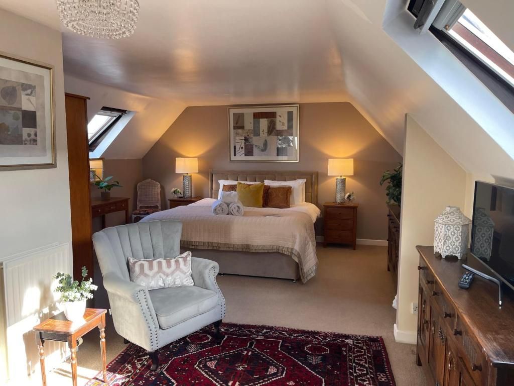 A bedroom with a bed, a chair, a TV, and a window.
