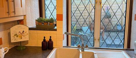 A kitchen with wooden cabinets, a double sink, and a window with a lattice design.