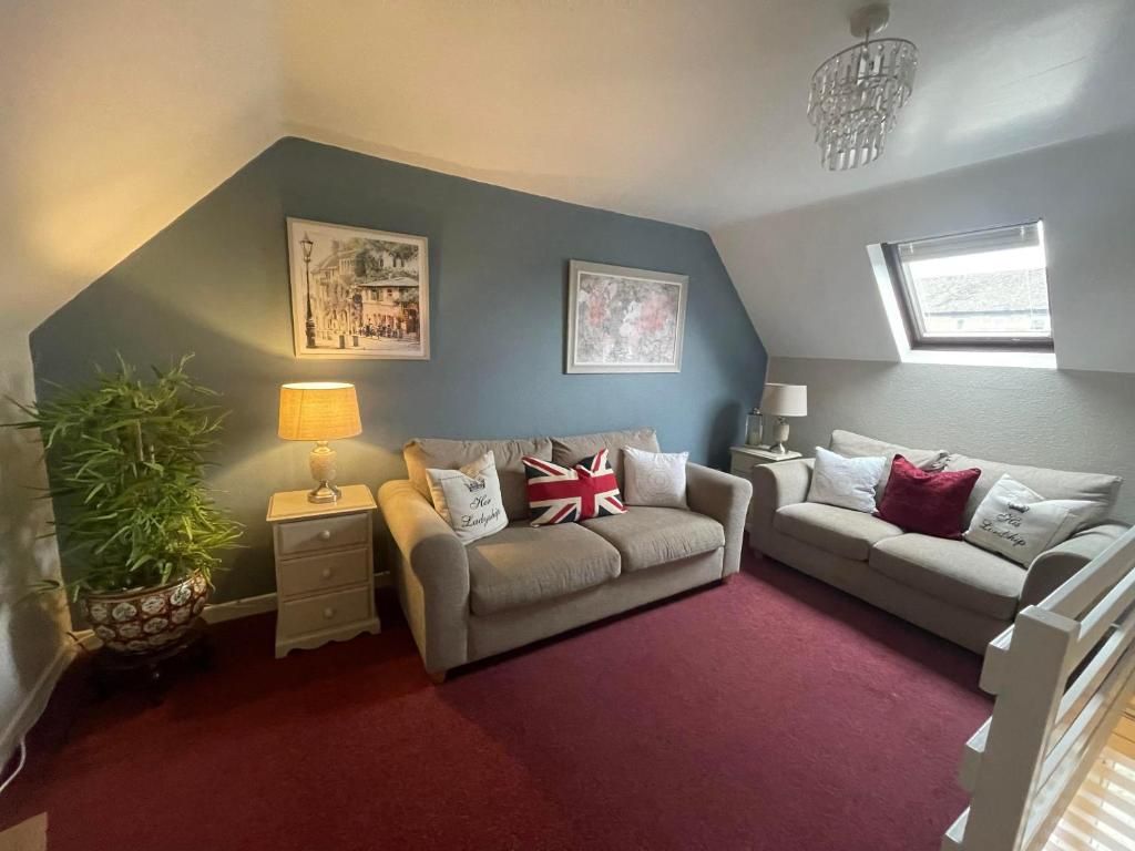 A cozy living room with two sofas, a small table, a lamp, and a potted plant.