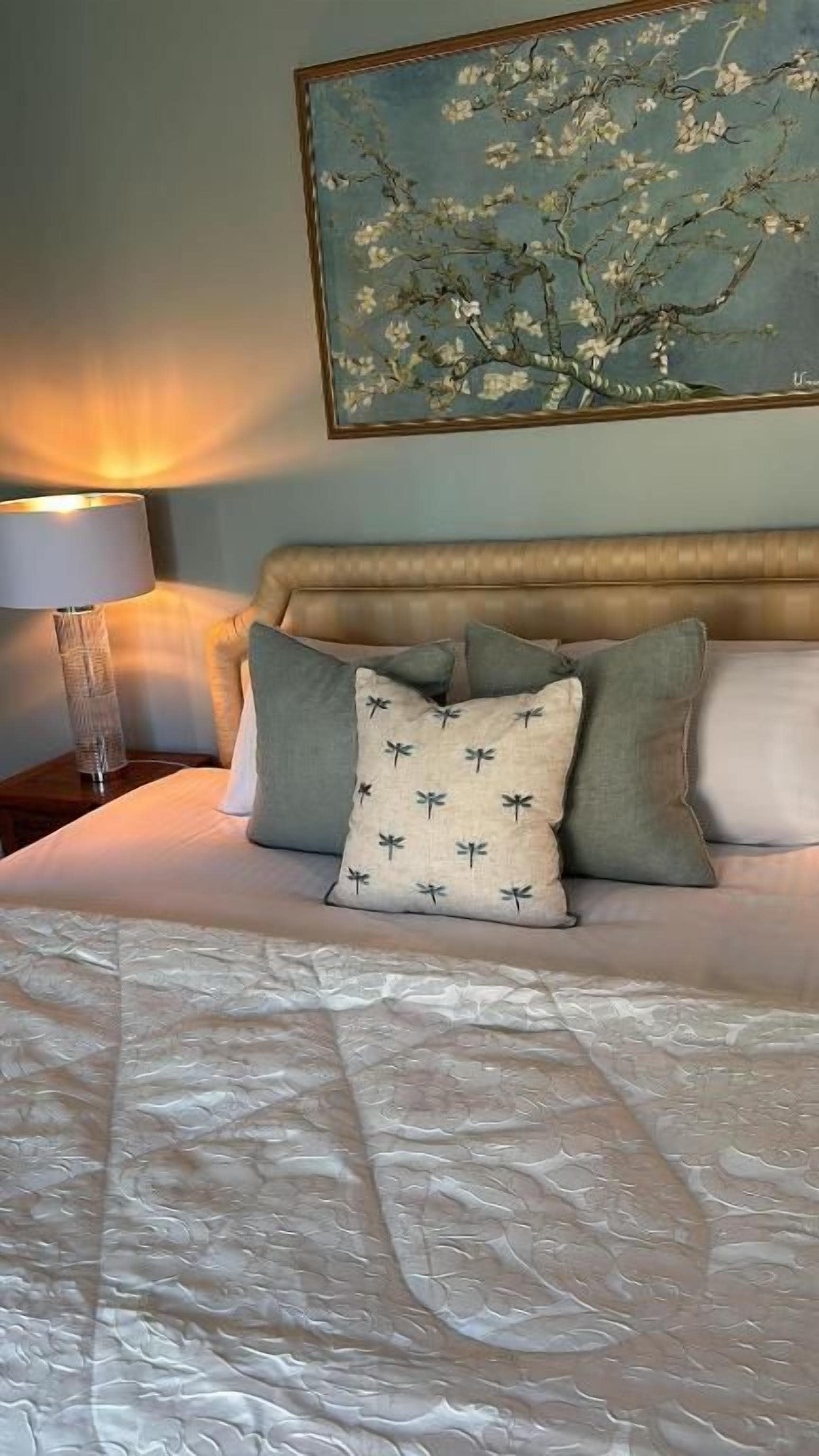A bed with a textured white cover, a headboard, and decorative pillows.