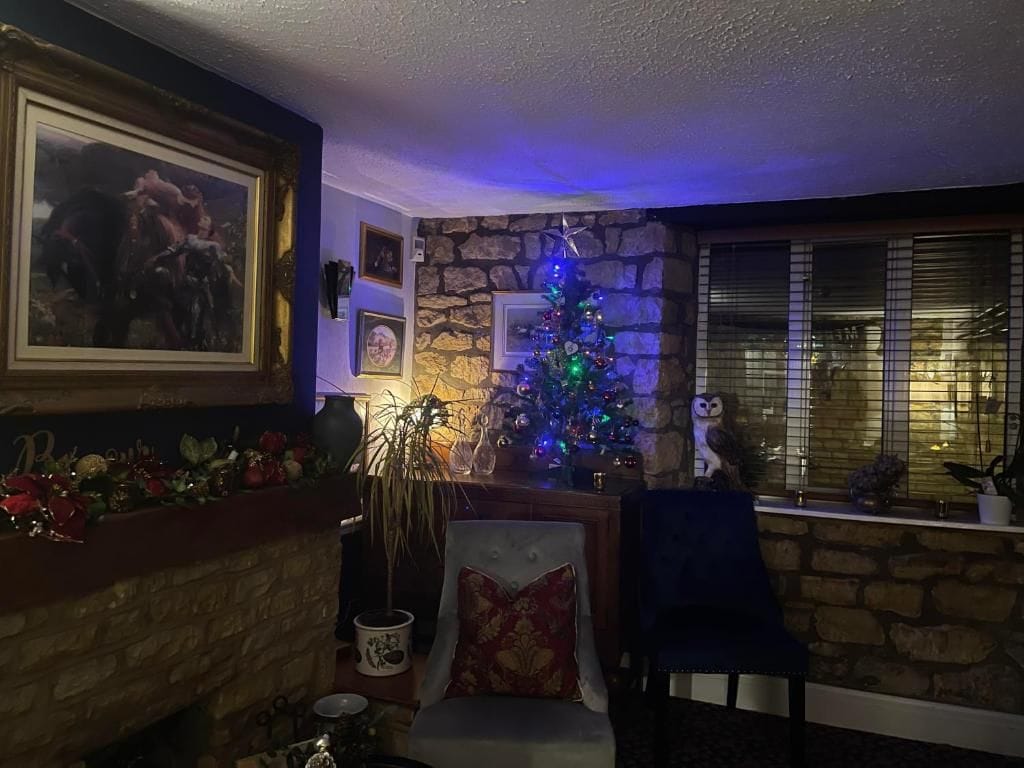 A living room with a stone fireplace, a Christmas tree, and a framed picture on the wall.
