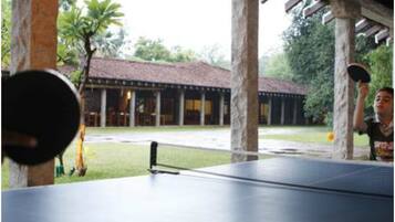 A table tennis table under a covered area with columns and a building in the background.