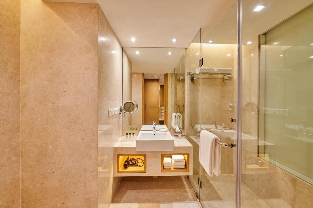 A modern bathroom with a glass-enclosed shower, a vanity with a sink, and a mirror.