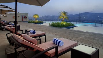 Relax on the rooftop terrace with lounge chairs, tables, and umbrellas, taking in the city views and surrounding hills.
