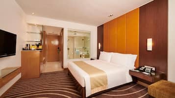 A hotel room with a bed, bedside table, TV, and a bathroom visible through an open door.