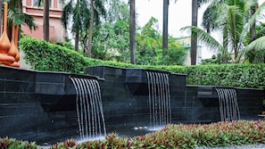 A water feature with multiple cascades, surrounded by greenery and palm trees. - Holiday Inn Mumbai International Airport by IHG (Mumbai)