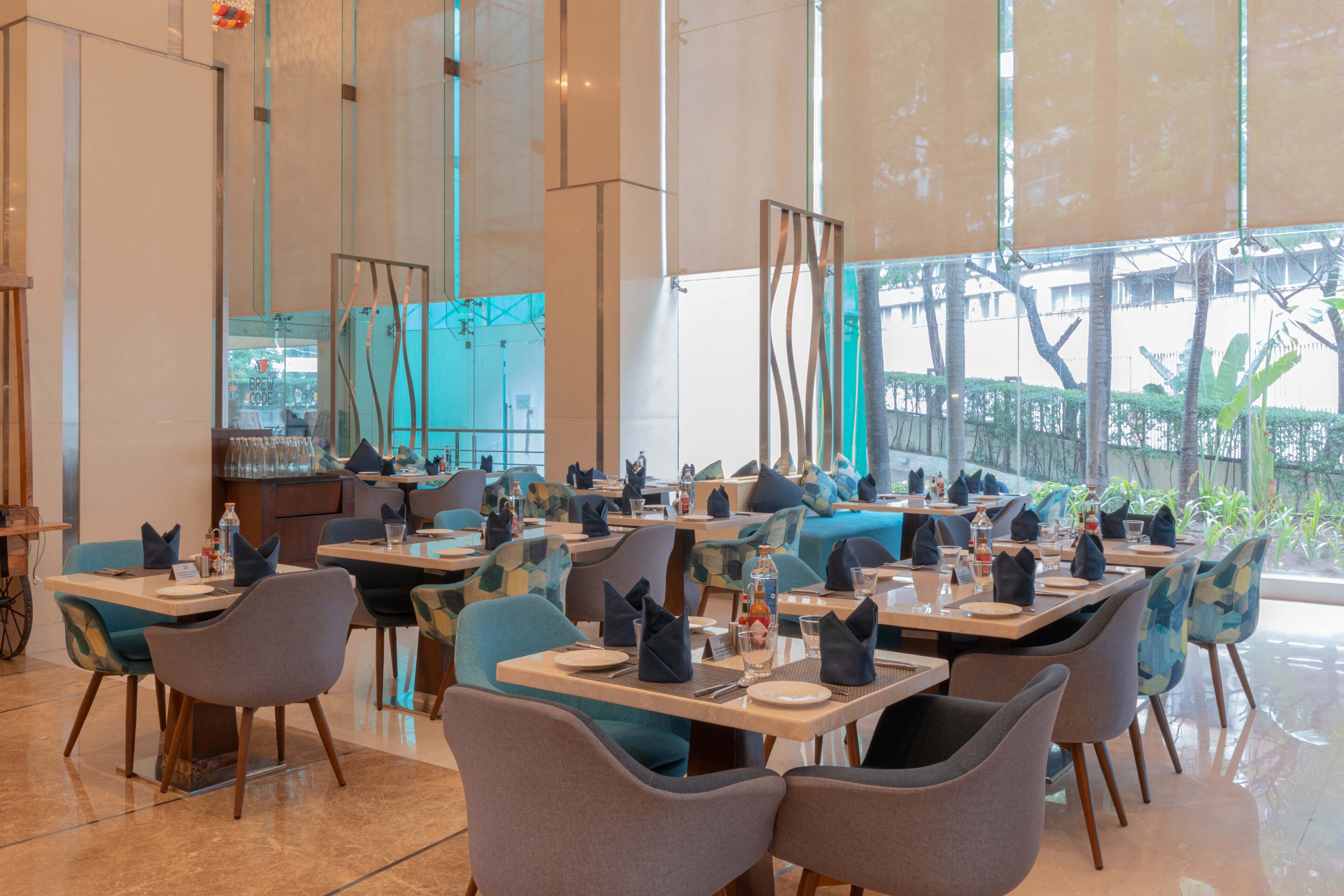 A modern restaurant with multiple tables and chairs, large windows, and a clean, contemporary interior design.