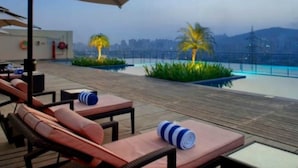 A rooftop terrace with lounge chairs and a pool.
