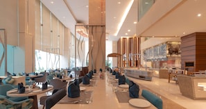 Un hall d'hôtel moderne avec une longue table à manger, des sièges et un espace bar.